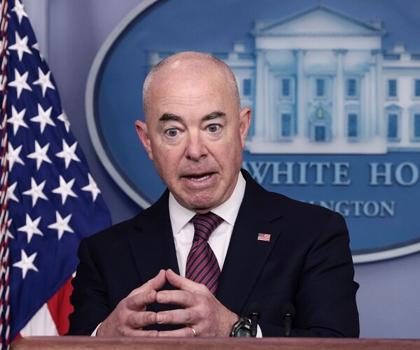 alejandro mayorkas gestures as he speaks from behind podium