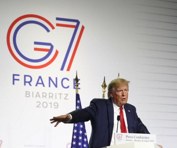 donald trump is shown talking to reporters with the g-7 france logo behind him