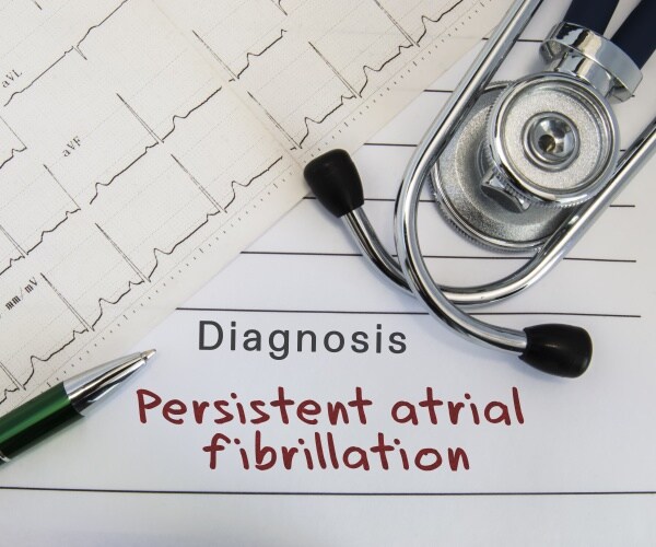 Diagnosis pad with 'persistent atrial fibrillation', a stethoscope, electrocardiogram