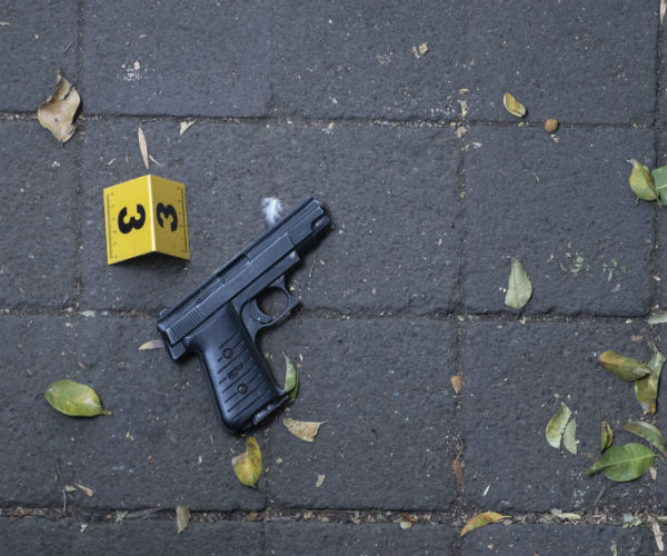 a pistol lies on the ground near a marker indicating it was used in a crime