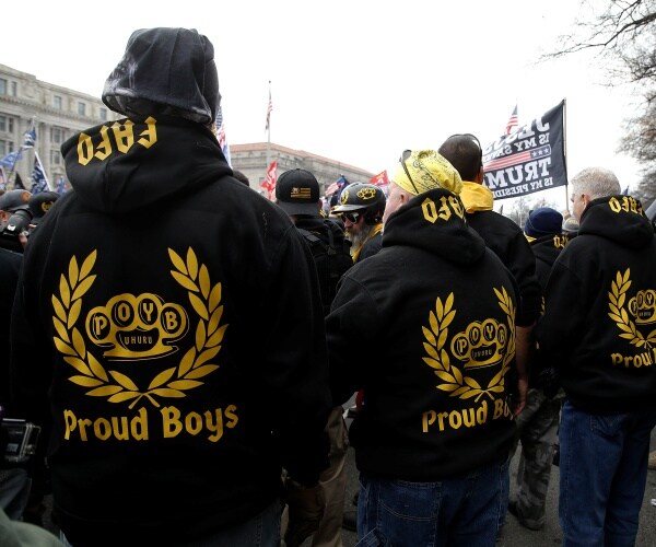 Proud boys wear black hoodies with yellow lettering at a rally