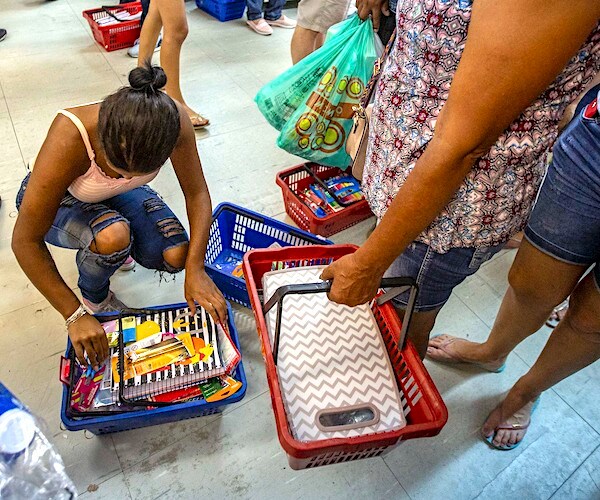 a women bends down to arrange her basket of school supplies in a busy retail store