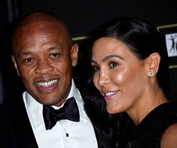 dr dre and nicole young stand on red carpet