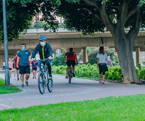 man wearing mask rides bike in park