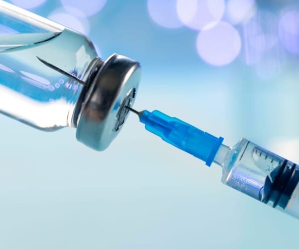 syringe in a vial of vaccine