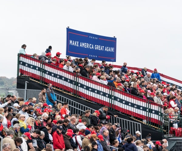 trump supporters attend a rally with a big blue "maga" sign