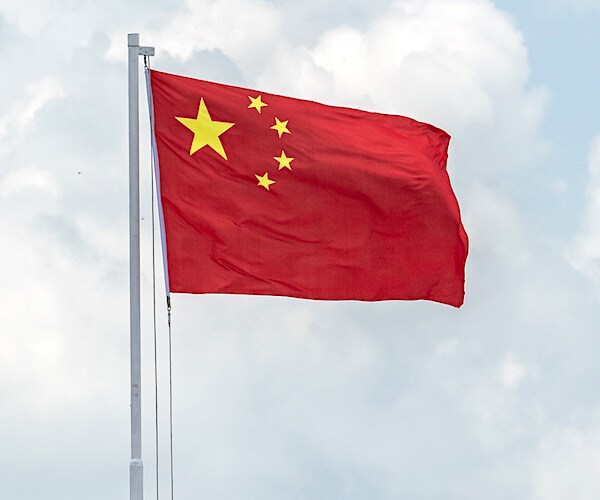 china's flag flies high amid a cloudy sky