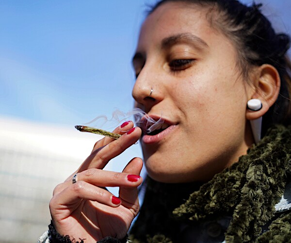a woman puffs smoke from a marijuana cigarette