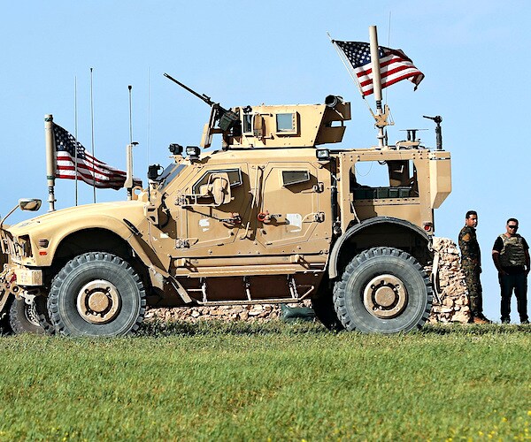 two soldiers stand to the right of a united states humvee donning american flags