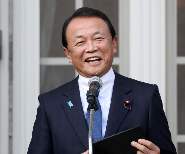 taro aso in a suit and blue tie speaking into a mic