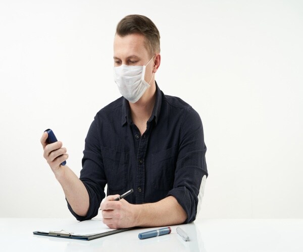 man with a mask on testing his insulin