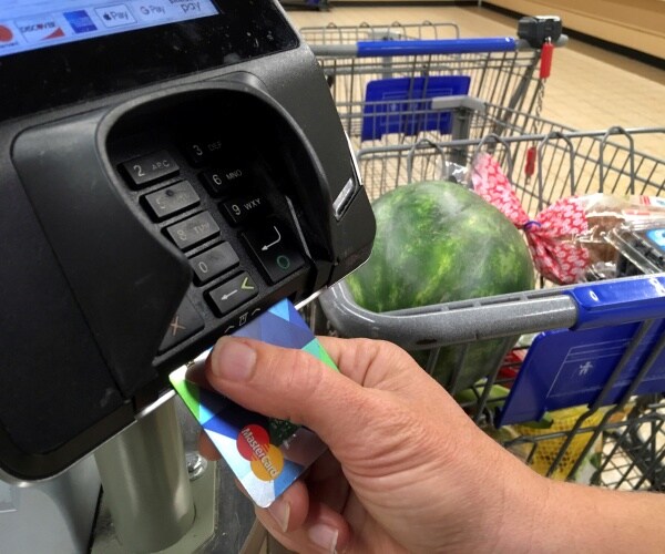 person inserts chip of a credit card into the reader while checking out at the grocery store