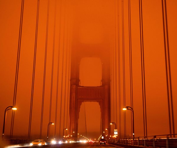 the Golden Gate Bridge under an orange smoke filled sky