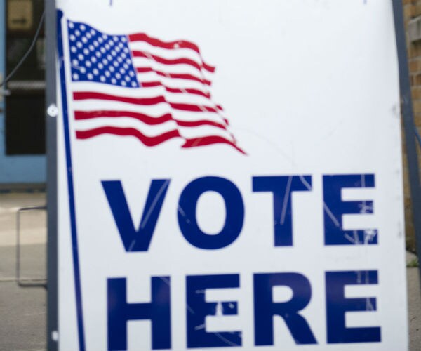 a us flag and a vote here sign is seen