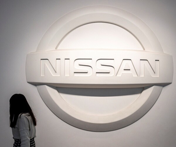 woman walks past nissan sign