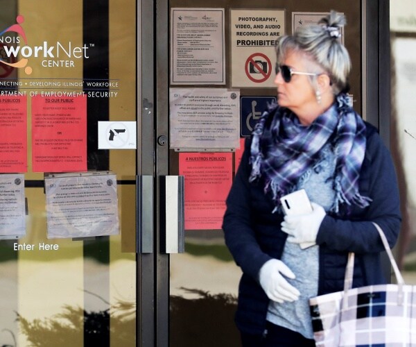 woman in a plaid scarf and tote bag looks through the window of a worknet center