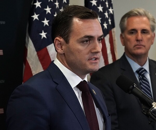 mike gallagher speaks in front of a flag