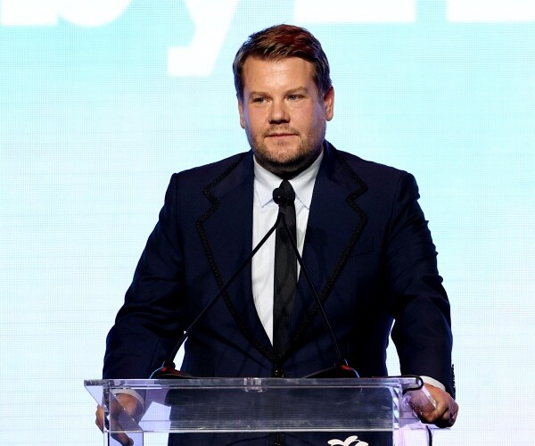 james corden stands behind podium onstage