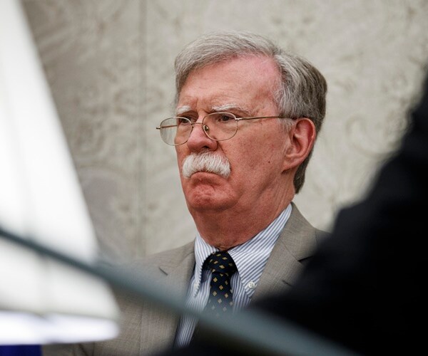 john bolton is obscured by foreground items in a photo of him seated in the oval office