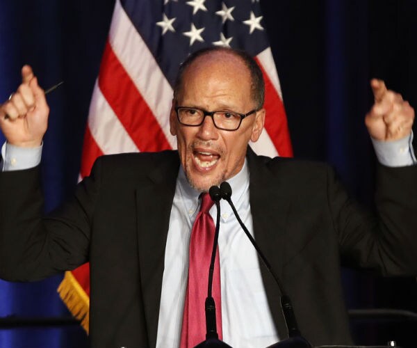 tom perez is shown with the american flag in the background