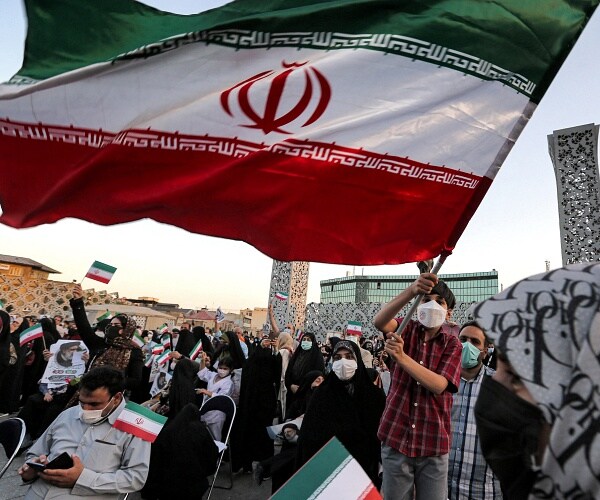 boy waves iranian flag in crowd