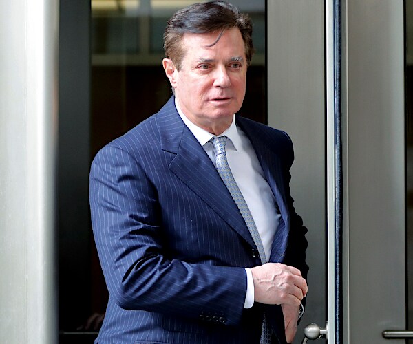 paul manafort walks briskly out of a building and past a throng of media