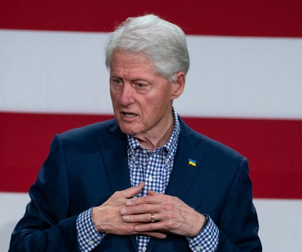 bill clinton stands in front of the u.s. flag