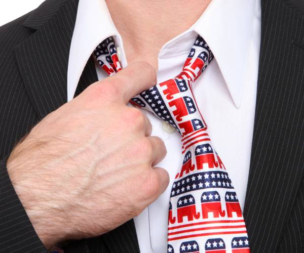 man loosening necktie that is decorated with republican logos