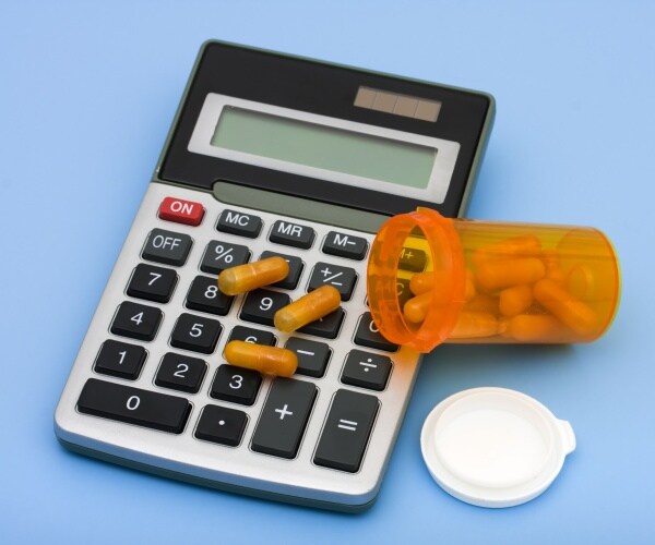 prescription drug vial, some capsules, on top of a calculator