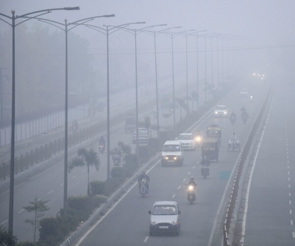 motorcycles and vans drive on a road in smog