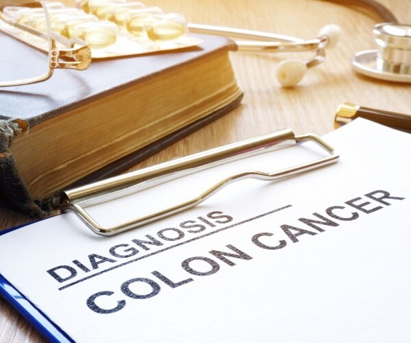 colon cancer diagnosis on a clipboard with a book and stethoscope on a desk
