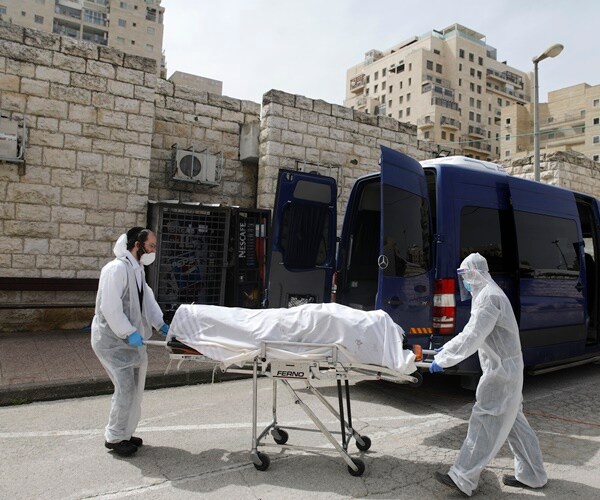 orthodox ambulance workers wheel the body of a person who died from coronavirus
