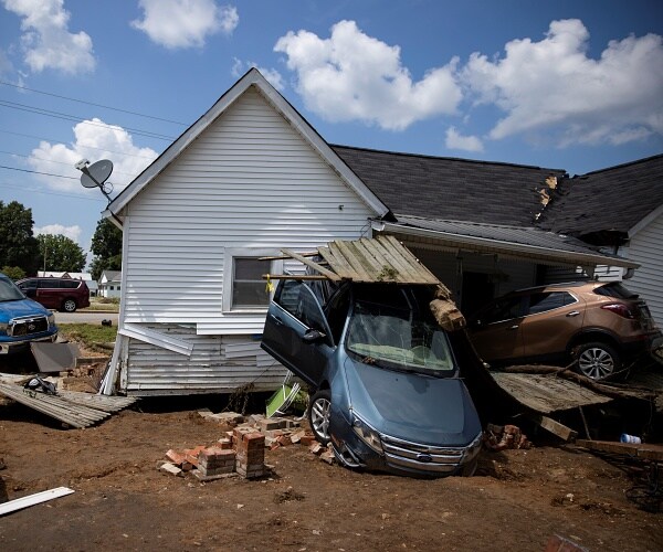 cars piled up next to destroyed house