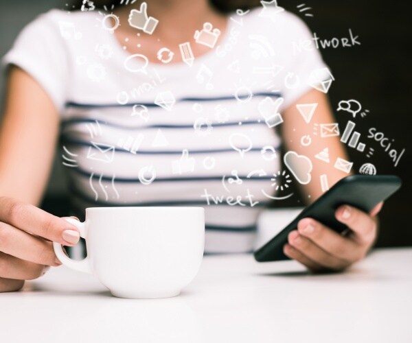 girl in a striped top using her smartphone and holding a coffee mug