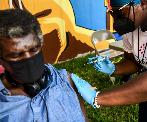 man gets coronavirus vaccine shot while sitting outside