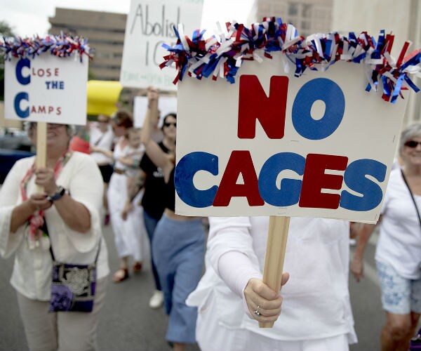 A woman holds a sign reading "No cages" during a protest in Texas.