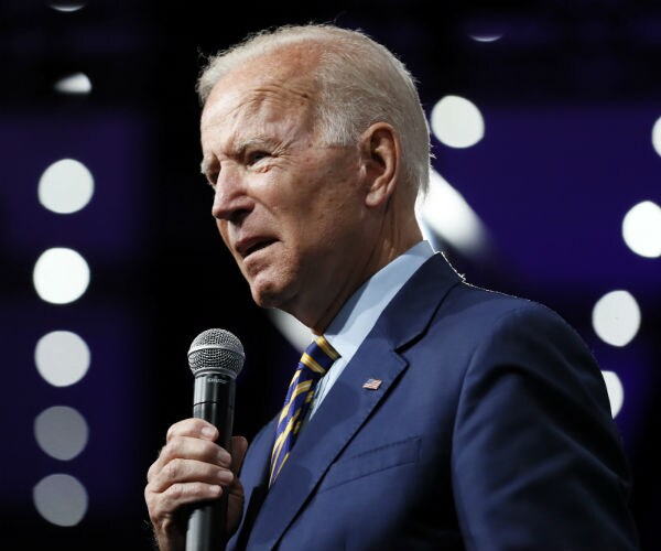 joe biden is seen speaking to an audience in a blue suit, dress shirt and tie