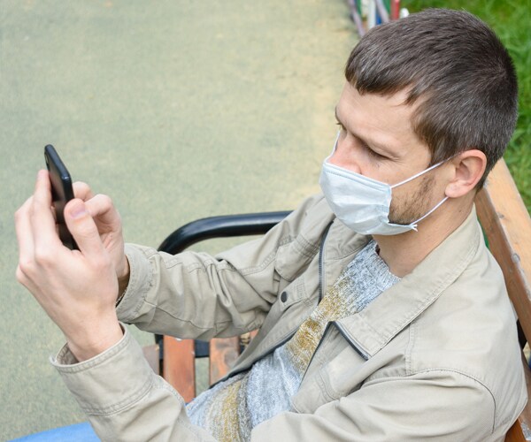 a man wearing a mask and using a cell phone