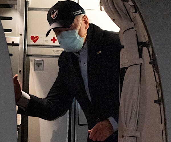 joe biden wears a mask as he bends down to exit his plane
