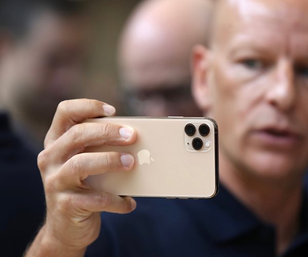 a man holds up an iPhone sideways to take a photo horizontally