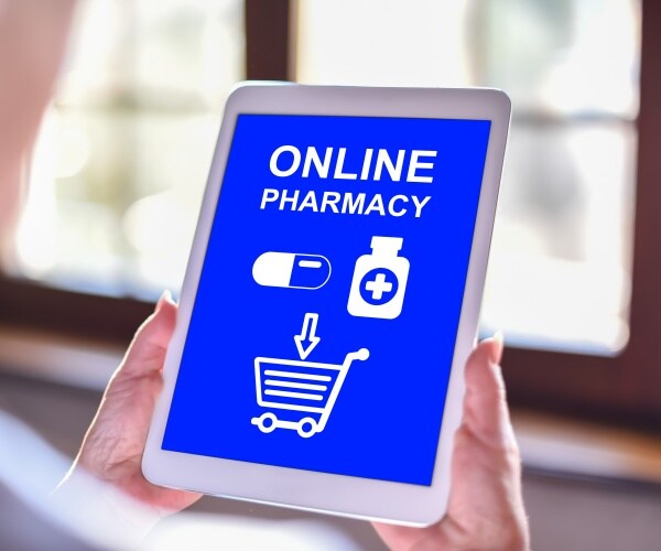 person holding a tablet with an online pharmacy up on the screen