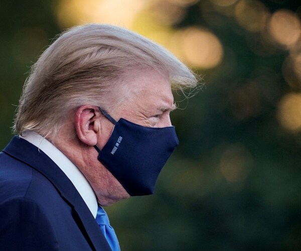 trump in a blue mask standing outside