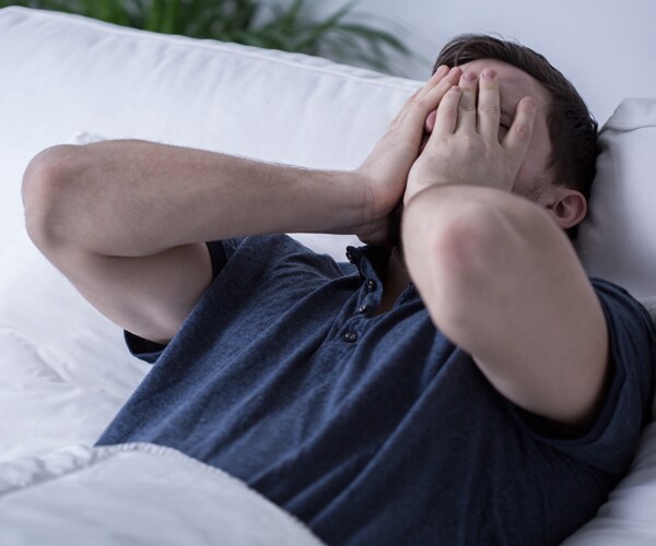 a man lying awake in bed with his hands on his face
