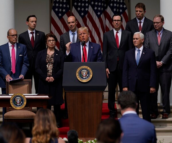 a group of white house staffers stand behind president donald trump during a speech