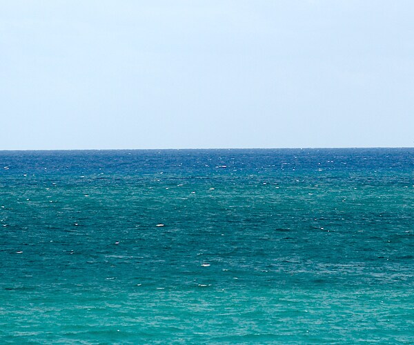 a long stretch of the atlantic ocean against a pale blue sky