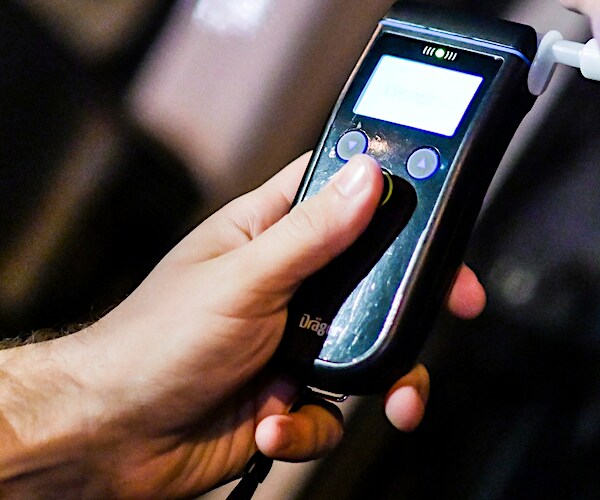 a police officer administers a breathalyzer with his left hand