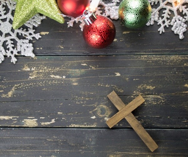 christmas holiday ornaments and a christian cross on a dark vintage wood background