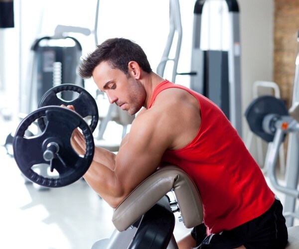 man in a red tank top lifting weights
