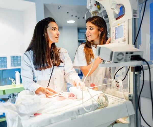 healthcare workers in hospital with premature baby in incubator