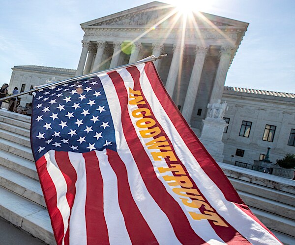 the steps of the supreme court with an american flag waving in front of him